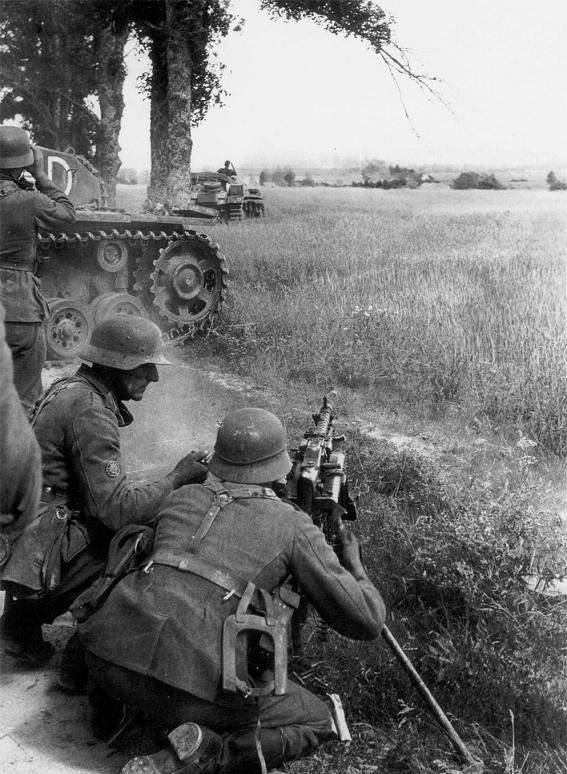 Пулеметный расчет немецких егерей ведет огонь из пулемета MG-34. Лето 1941 года, группа армий «Север». На заднем плане расчет прикрывает САУ StuG III. Время съемки: лето 1941